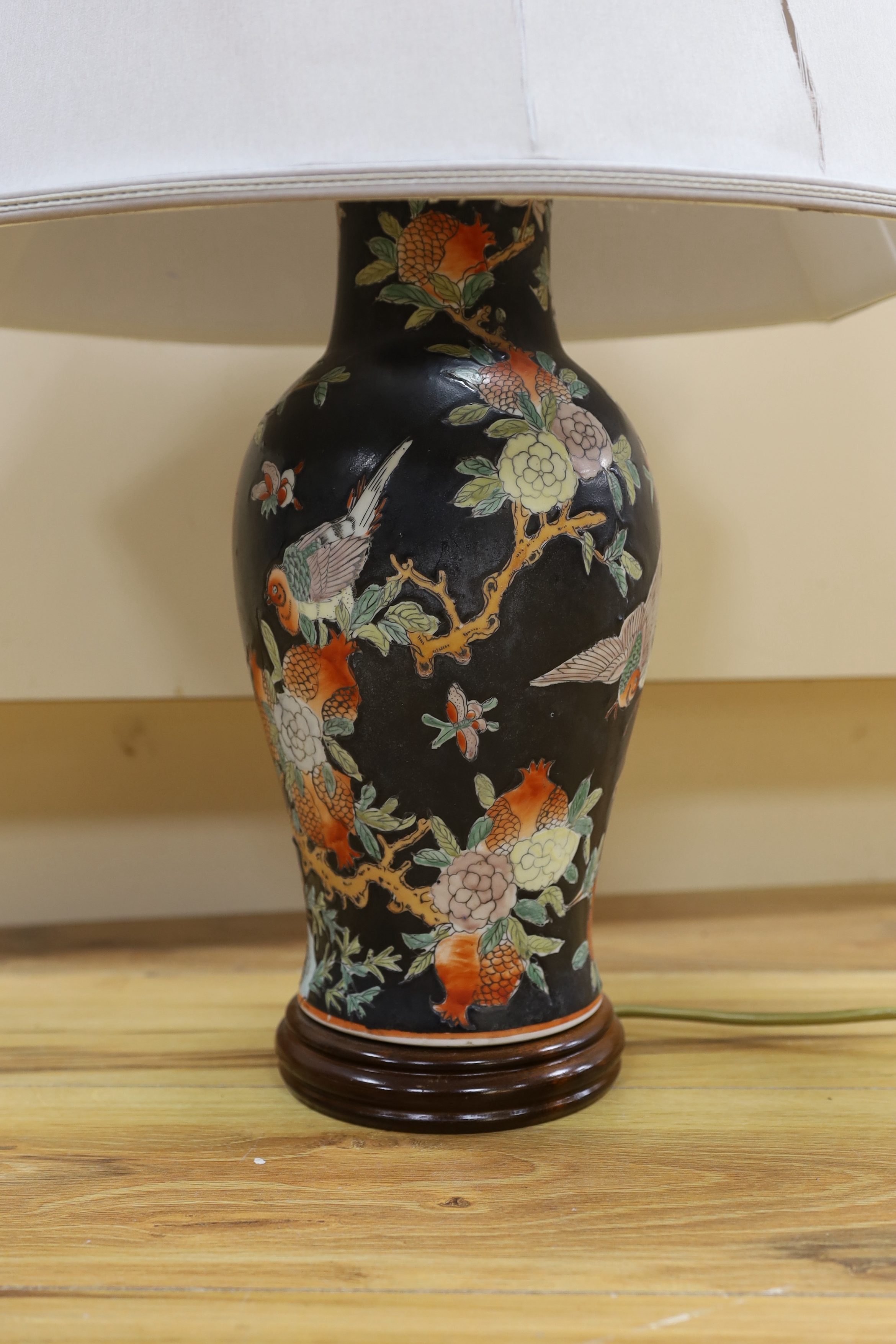 A Chinese famille noire table lamp and a pink ground Chinese vase, both on wooden stands, tallest vase 39cm